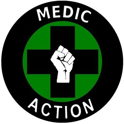 Logo de Medic'action: Un cercle noir entoure une croix noir avec un poing levé blanc le tout sur un arriere plan vert.